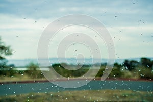 Drops of rain on the window; blurred landscape in the background