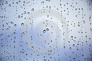 Drops of rain on a window glass. Beautiful blue cloudy sky in background