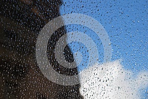 Drops of rain on the window, sky, cloud and silhouette of the building