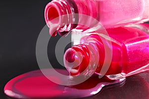 drops of red bearded pink nail polish flow from the bottle of the bottle on a black dark background with a copyspace