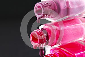 drops of red bearded pink nail polish flow from the bottle of the bottle on a black dark background with a copyspace