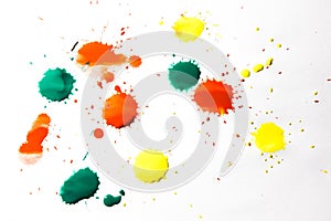 Drops of red, yellow and green paint are sprayed on a white background