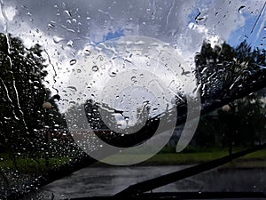 Drops shower on the windshield of a car glass after heavy rain and thunderstorm. Rural scene. Selective focus