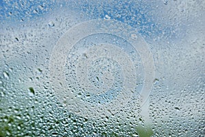 drops of summer rain on the window glass of fresh blue and white