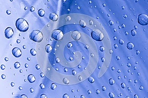 Drops of water on a blue metal surface. Abstract blue background made of water drops. Selective focus