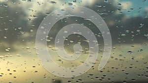 Drops of water fall on the windshield of a car during rain.