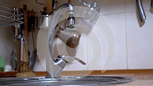 Drops of Water Falls into Sink from the Kitchen Faucet or Mixer. Home Kitchen.