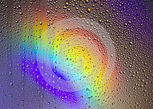 Drops of water on the glass, with the reflection of the rainbow