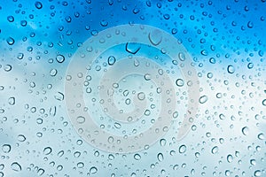 Drops of water on glass window over blue sky .