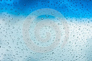 Drops of water on glass window over blue sky .