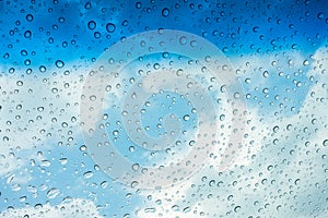 Drops of water on glass window over blue sky .