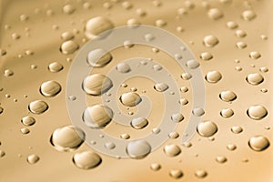 Drops of water on a golden metal surface. Abstract golden background made of water drops. Selective focus