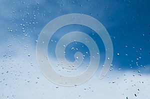 Drops of water from the rain on the glass. Window. Against the background of blue sky. Freshness of summer