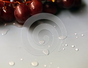 Drops of Water and Some Purple Grapes on a Light Blue Surface