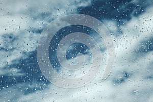 Drops on window, blue sky with clouds on background