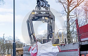 Dropside flatbed HIAB crane lorry with brick grab attachment deliver materials on construction site and offloading them