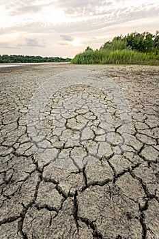 Drought and climate change, landscape of cracked earth with orange sky after lake has dried up in summer. Water crisis an impact
