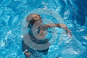 Drowning kid into swimming pool water. Boy
