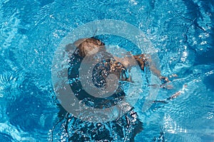 Drowning kid into swimming pool water. Boy