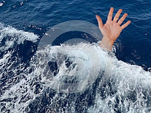 A drowning man asks for help. The hand of a man in the deep sea. Sticking your hand out of the sea water. Concept: rescue drowning