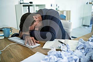 Drowning in paperwork. Shot of a stressed out businessman passed out at his desk overwhelmed by paperwork.