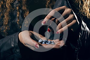 Drug abuse. Woman with pills in hand taking one.