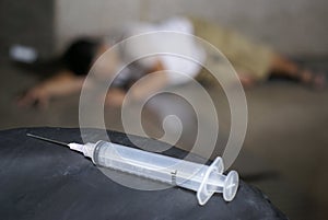 Drug addict and syringe on floor