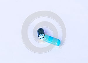 Drug capsule blue decisive damaged have white powder inside on white background.