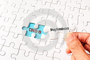 The drug remdesivir word on white jigsaw puzzle go to replace COVID-19 word on blue gap - idea answer concept photo
