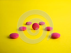 Drug. Round red tablets on a yellow background. Medicine, pharmaceuticals