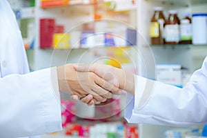 Drug store of pharmacist shaking hands with a client at the pharmacy , health concept