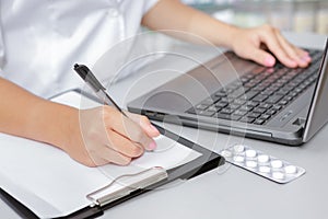 Druggist making notes from the laptop