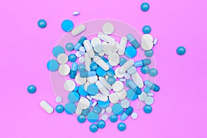 Drugs capsules and pills on pink background.