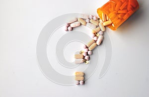Drugs and health supplement pills in a question mark