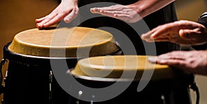 Drum. Hands of a musician playing on bongs. The musician plays the bongo. Close up of musician hand playing bongos drums