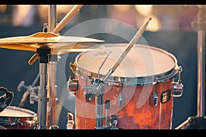 Drum kit on outdoor stage, drumsticks resting on tom tom drum
