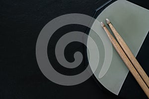 Drum stick and drum pad on black table background, top view, music concept