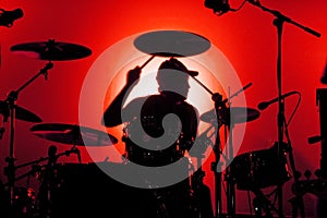 Silhouette di un batterista in uno sfondo rosso.