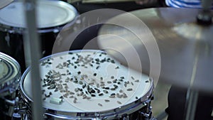 Drummer beats the snare drum with sunflower seeds, seeds bounce off, jumps. Drums stand on the road