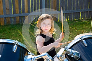 Drummer blond kid girl playing drums in tha backyard