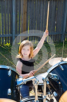 Drummer blond kid girl playing drums in tha backyard