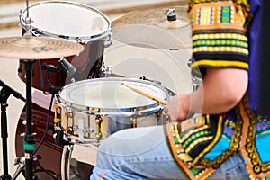 Drummer man playing drums percussion with sticks, drum kit on concert stage, drumsticks and drums