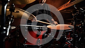 Drummer playing drum kit on stage against background of light and smoke. A male musician is passionate about performing