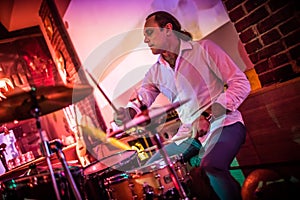 Drummer playing on drum set on stage.