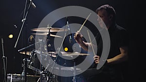 Drummer playing drums during rock concert on stage with spotlights. Live concert. Slow motion