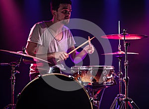 The drummer plays the drums. Beautiful blue and red background, with rays of light. Beautiful special effects smoke and lighting