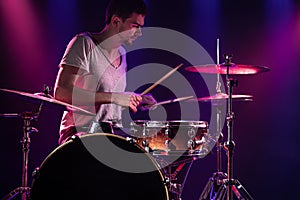 The drummer plays the drums. Beautiful blue and red background, with rays of light. Beautiful special effects smoke and lighting