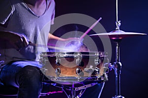 A drummer plays drums on a blue background. Beautiful special effects of light and smoke