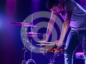 A drummer plays drums on a blue background. Beautiful special effects of light and smoke