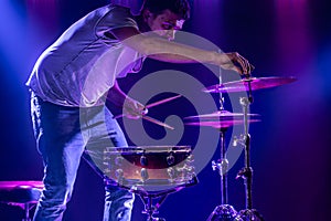 A drummer plays drums on a blue background. Beautiful special effects of light and smoke